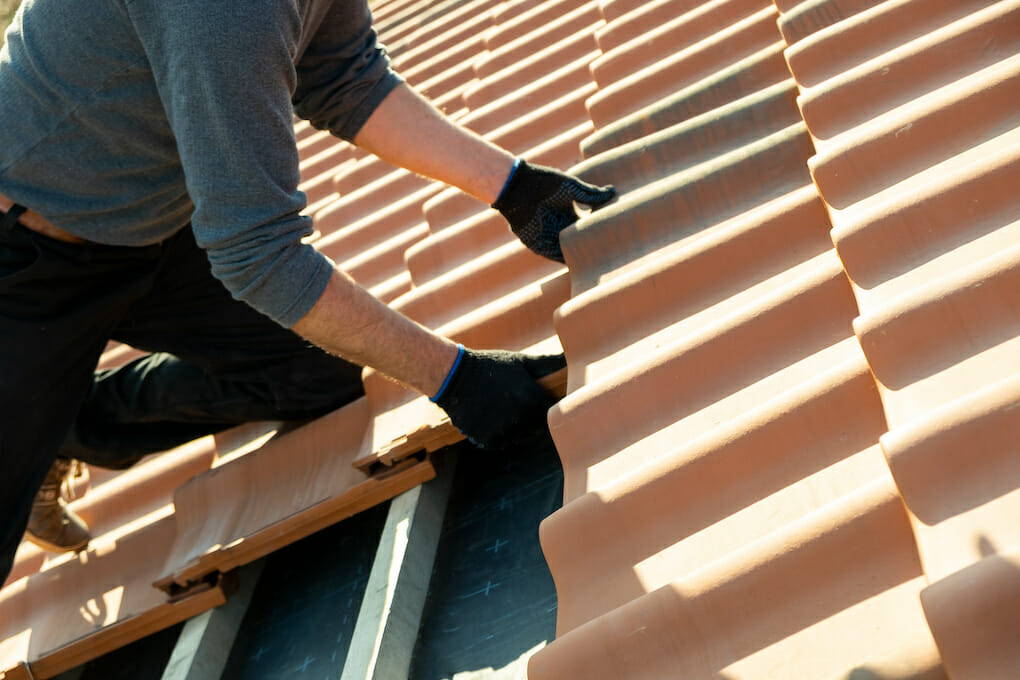 worker installing roofing materials on house