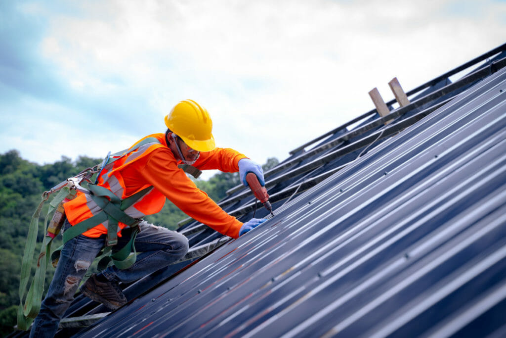 metal roof installation with worker in orange shirt