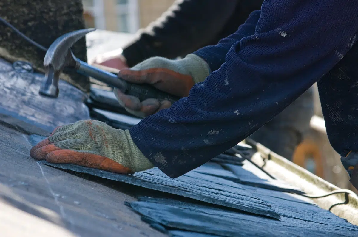 contractor assesses slate roof tiles for installation